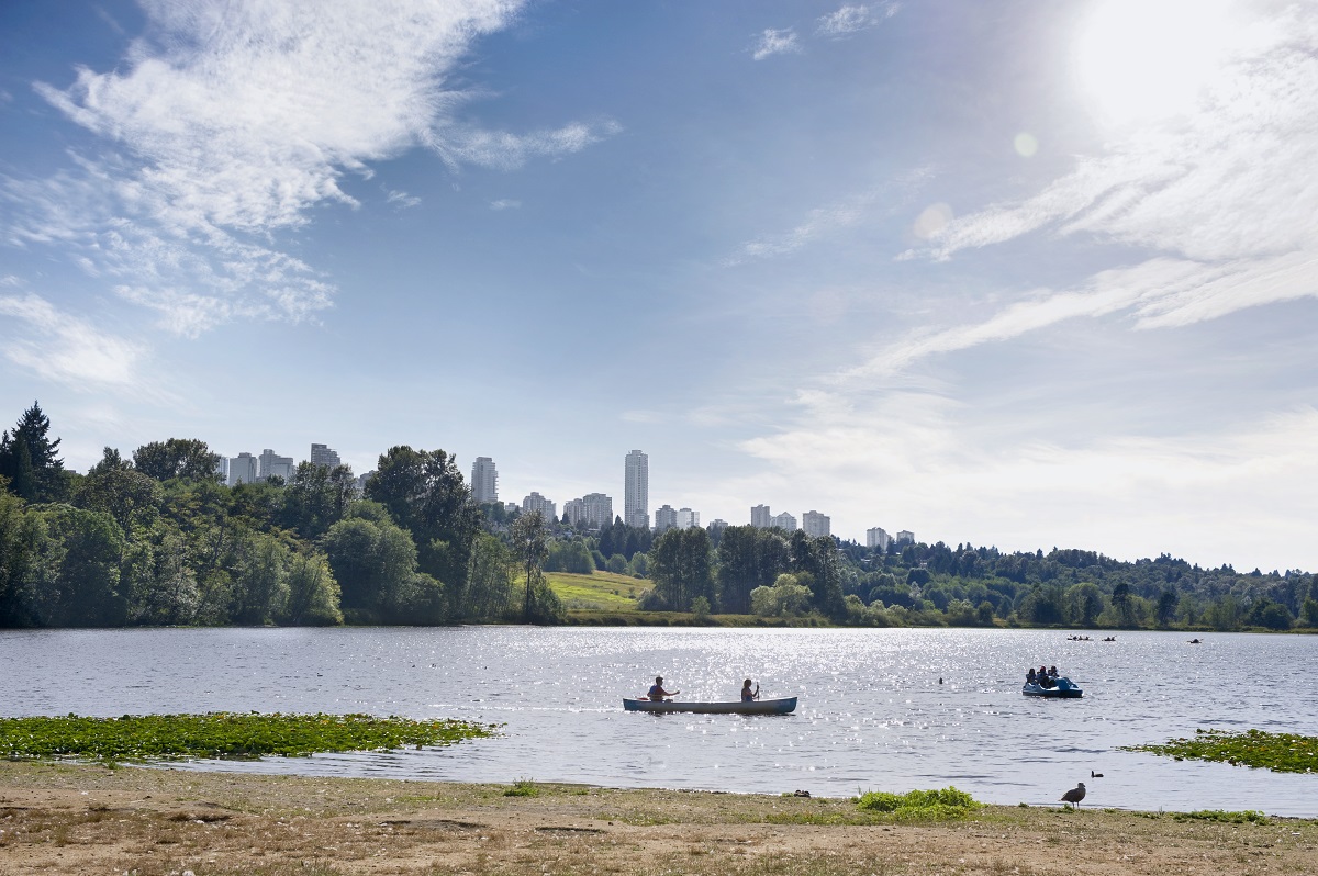 Two people paddle a canoe on a sunny day at Deer Lake in Burnaby