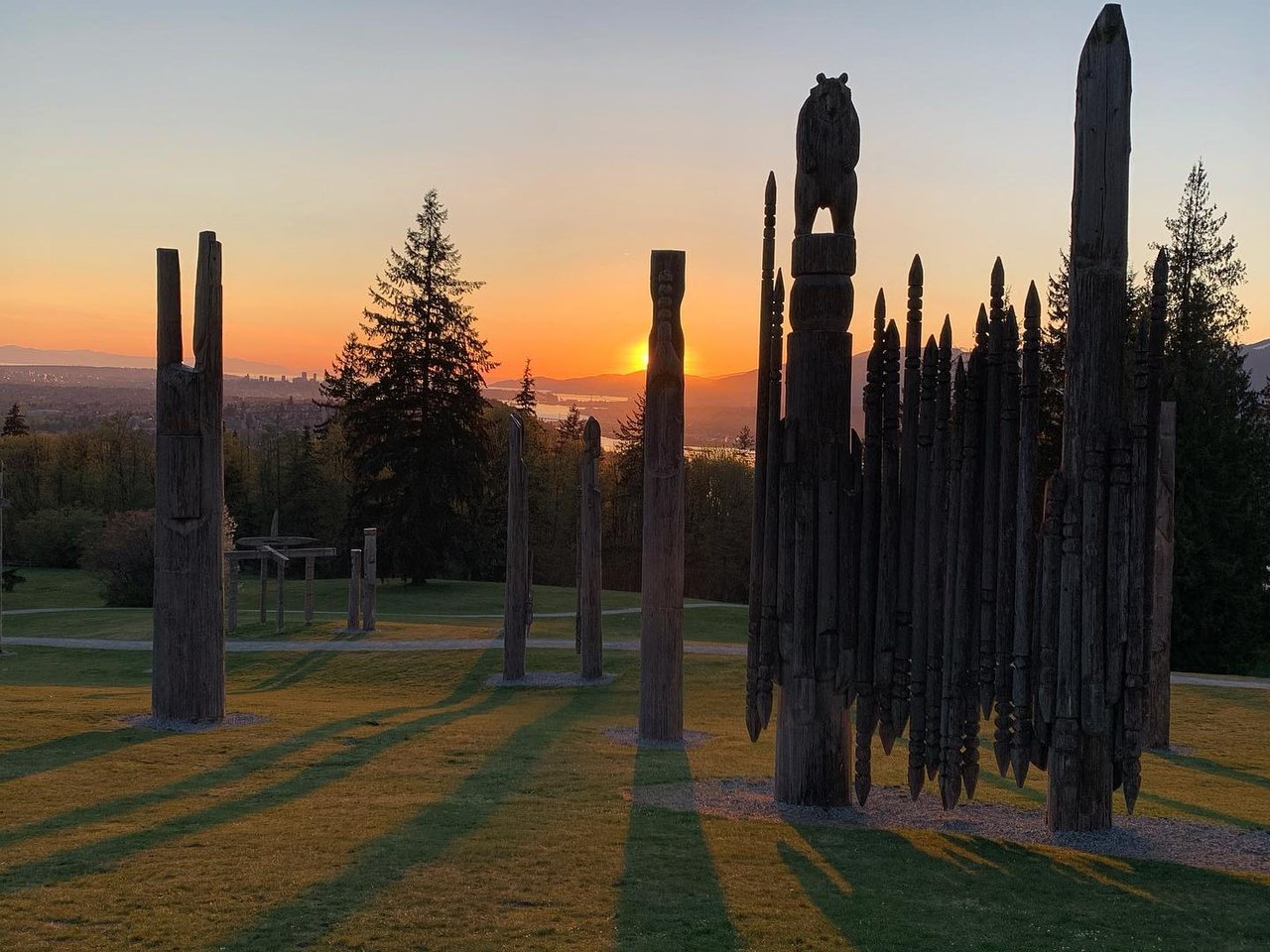 Collection of Totem Poles on the top of Burnaby mountain with the sun setting behind them