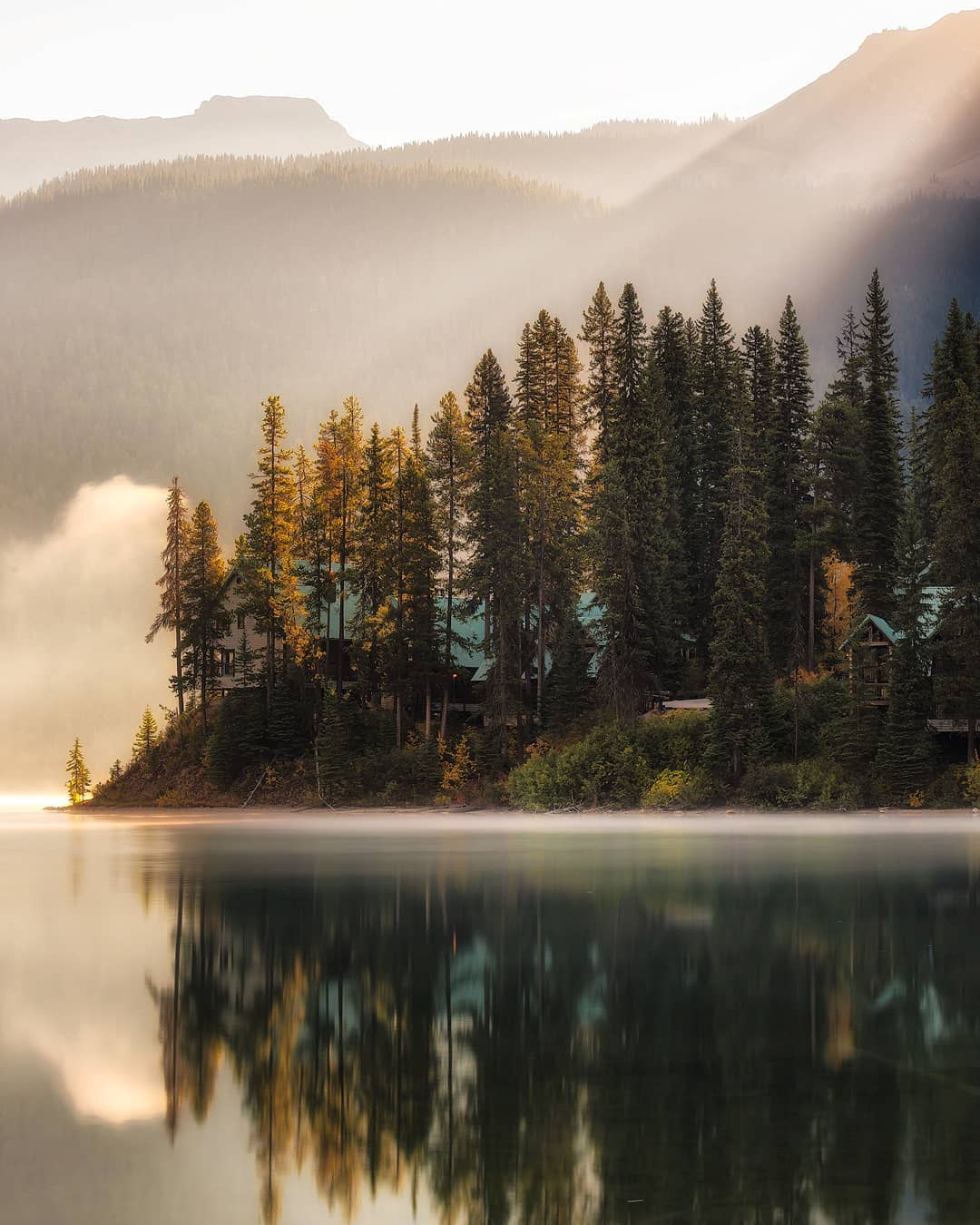 Fall morning on Emerald Lake. The light shines down on the lake over a small island with trees.